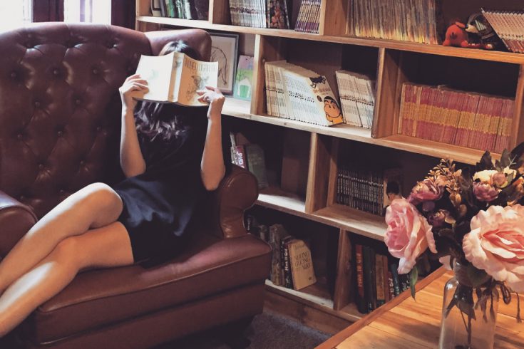 Lesende Frau mit Bücherregal im Hintergrund